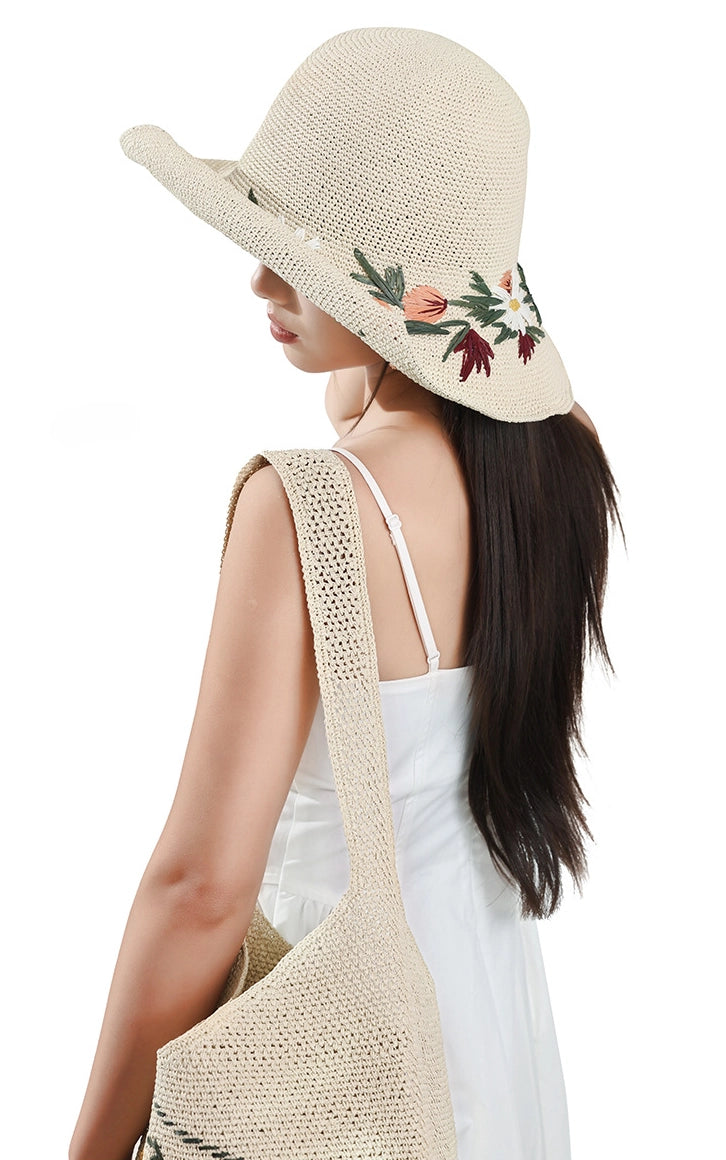 Back view of floral embroidered wide brim straw sun hat with ivory woven shoulder bag