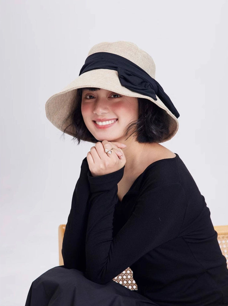 Model wearing a beige wide brim bow sun hat with foldable design for summer travel and casual resort style.