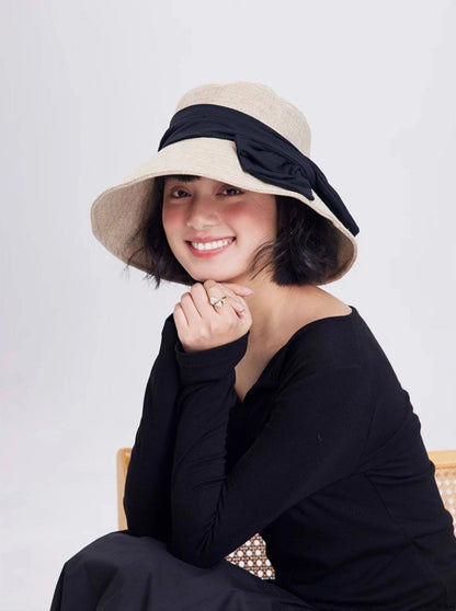 Model wearing a beige wide brim bow sun hat with foldable design for summer travel and casual resort style.