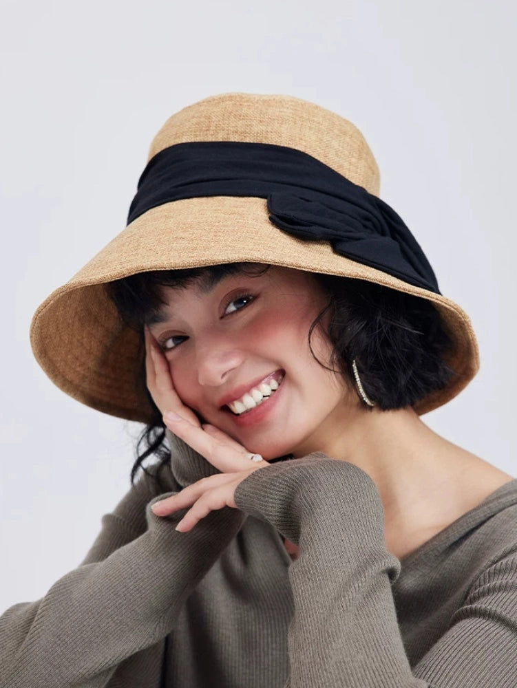 Model wearing a natural flax wide brim bow sun hat with elegant ribbon accent for summer travel and resort style.