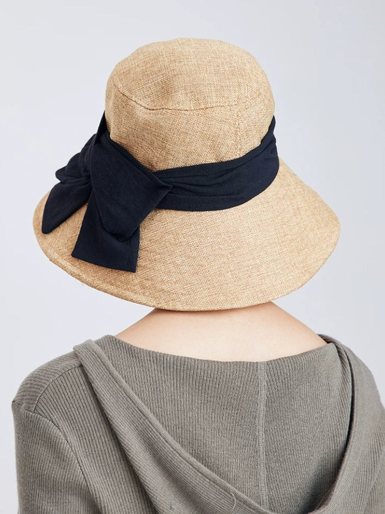 Rear view of natural flax wide brim sun hat with black bow ribbon and adjustable fit for travel and daily wear.