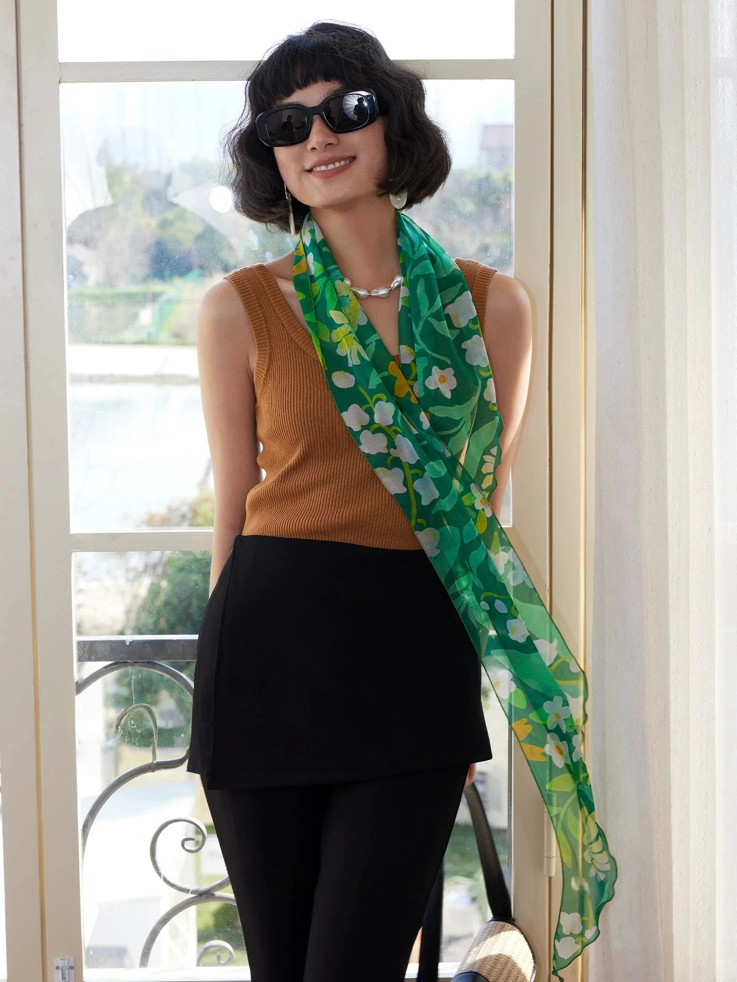 Model wearing a forest green botanical skinny silk scarf with sleeveless top for elegant summer styling