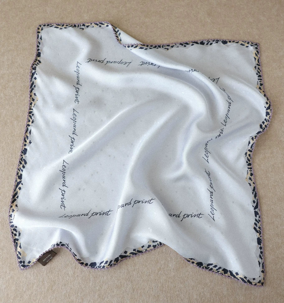 Glacier blue silk square scarf with cursive script and leopard-print border displayed flat