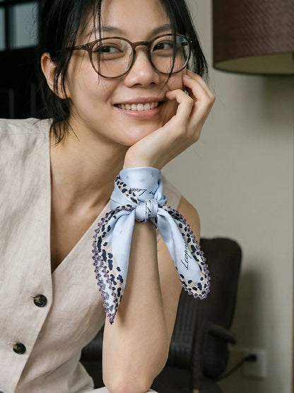 Glacier blue leopard-trim silk scarf styled as an elegant wrist wrap