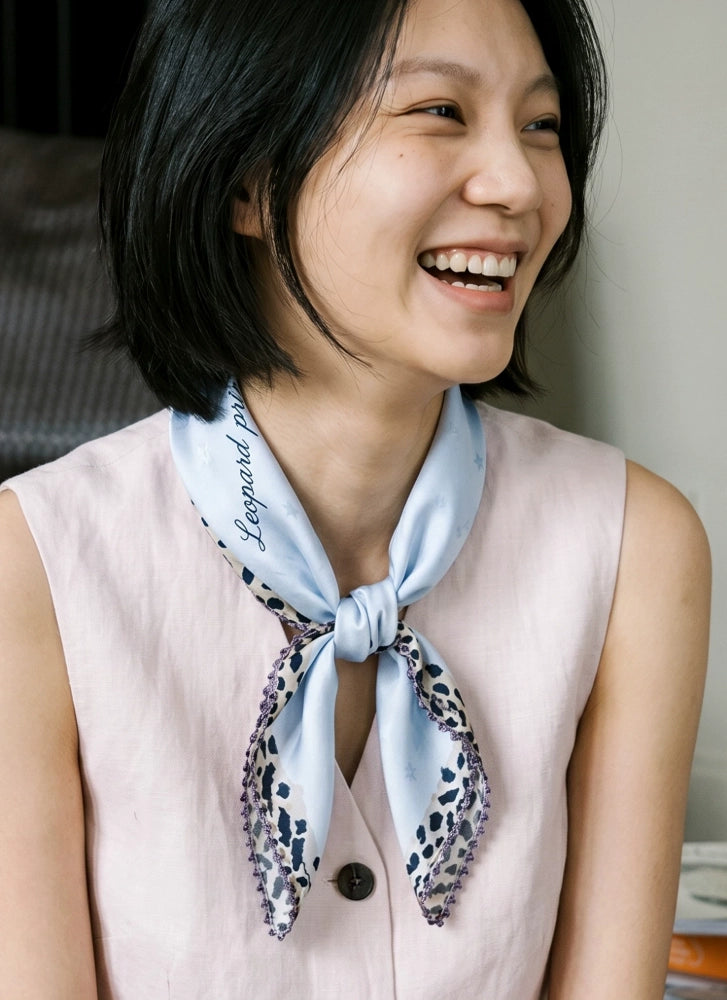 Woman wearing a glacier blue mulberry silk neckerchief with a sleeveless pink blouse