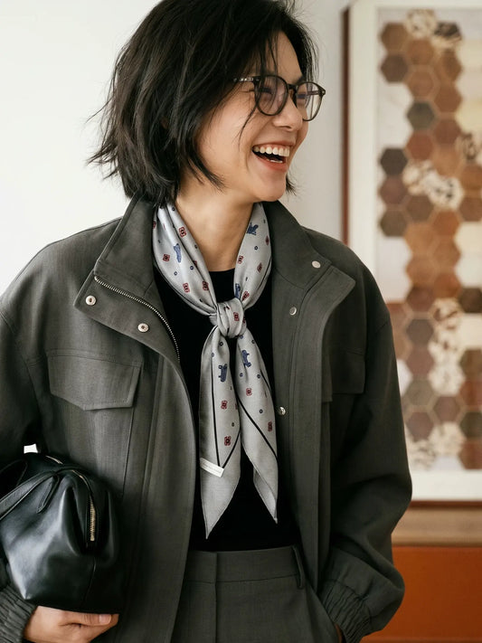 Side view of gray floral silk wool diamond scarf styled with a black top and olive jacket