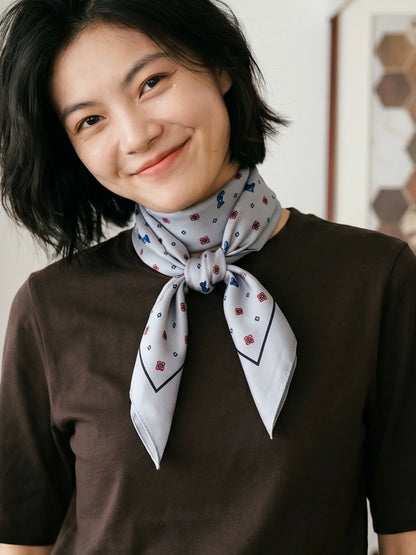 Gray ditsy floral silk wool scarf tied at the neck with a brown knit top