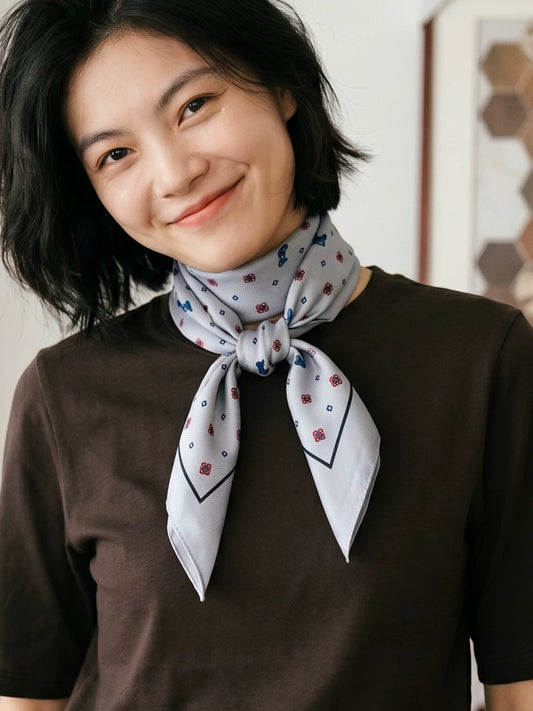 Gray ditsy floral silk wool scarf tied at the neck with a brown knit top