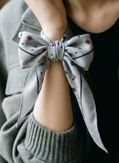Gray ditsy floral silk wool scarf tied in a bow around the wrist