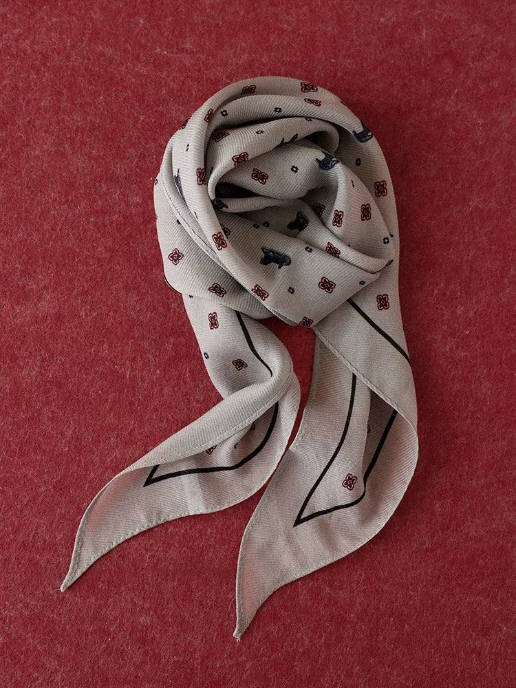 Gray ditsy floral diamond scarf coiled on a burgundy textured background