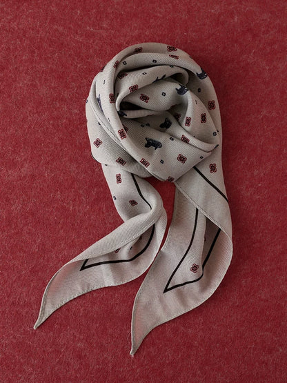 Gray ditsy floral diamond scarf coiled on a burgundy textured background