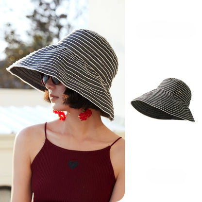 Woman wearing a gray and white striped foldable wide brim sun hat with an adjustable chin strap.