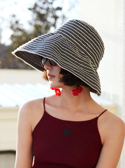 Side view of a gray and white striped wide brim sun hat styled for an elegant summer outing.