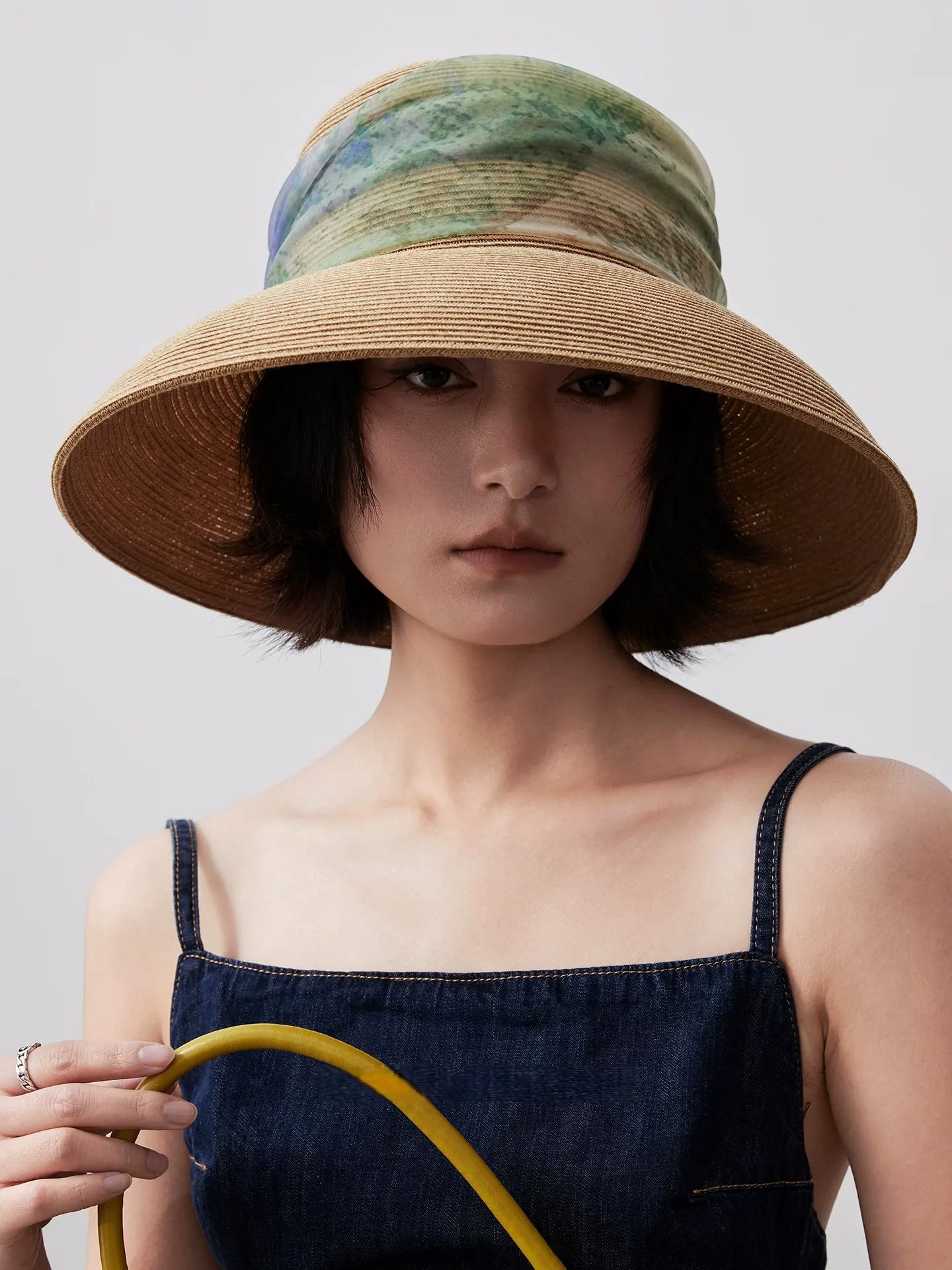 Woman wearing herbal beige scarf ribbon wide brim sun hat with navy summer dress.