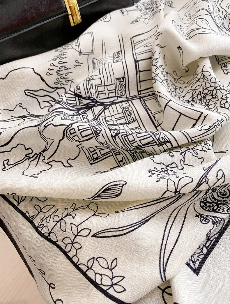 Close-up of cityscape line art and navy border on an ivory mulberry silk wool scarf