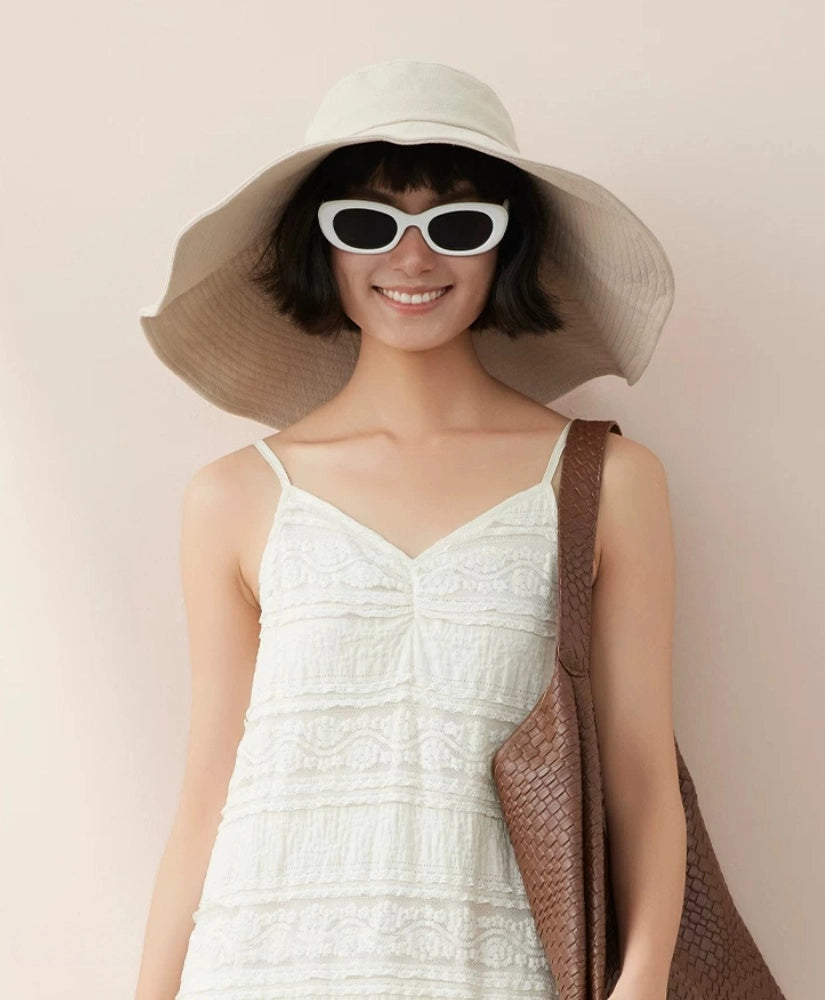 Woman styling ivory cotton wide brim sun hat with sunglasses for elegant summer beach wear