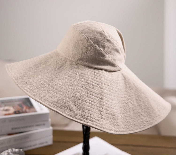 Ivory cotton oversized wide brim sun hat displayed on table with foldable brim and wind cord