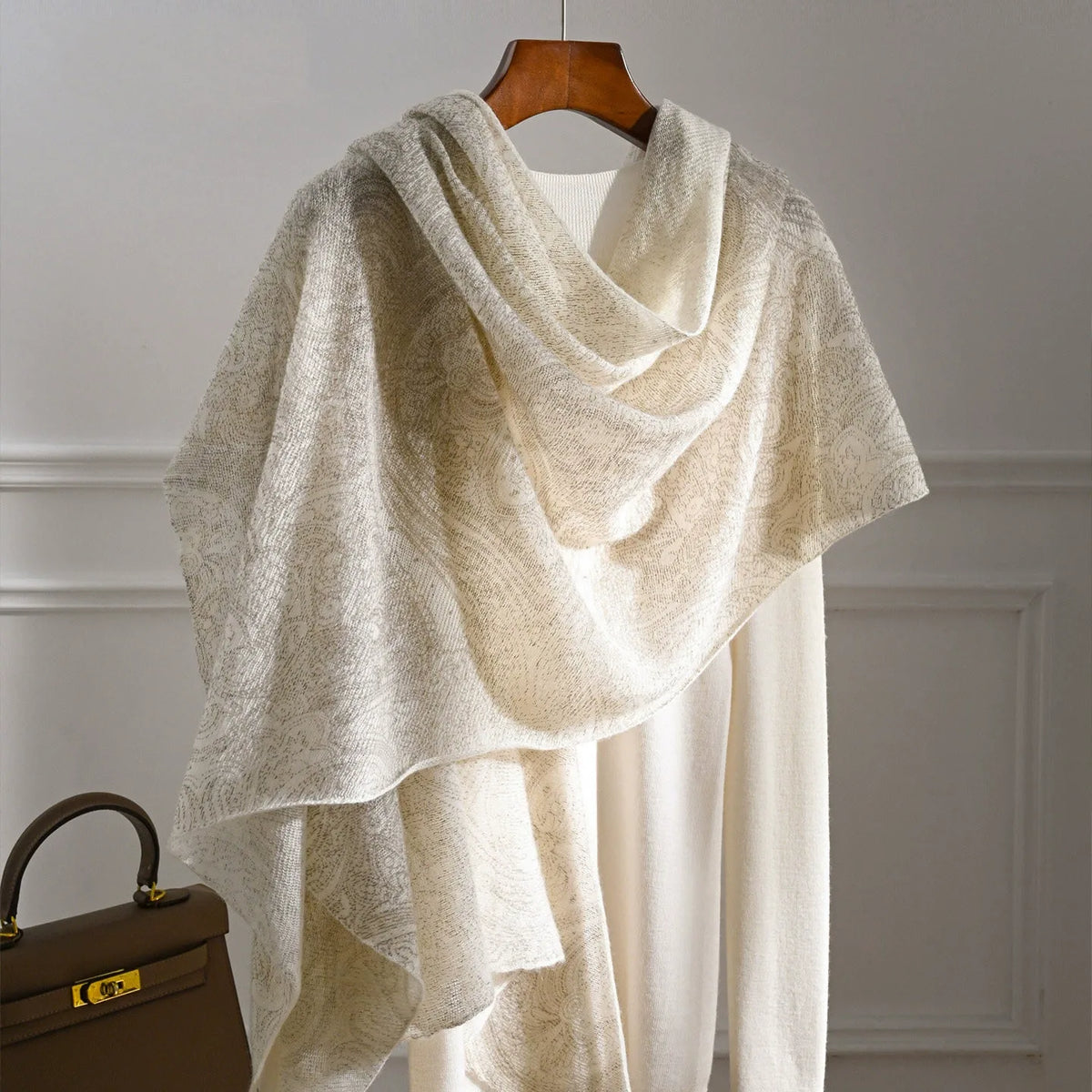 Ivory cashmere scarf with a subtle tonal pattern draped over a cream knit top.