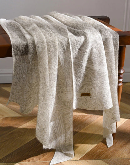 Ivory lightweight cashmere scarf draped over a wooden chair, showing its length and flowing folds.