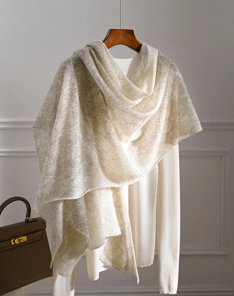 Ivory cashmere shawl styled over a cream top with an asymmetrical drape and long hanging ends.