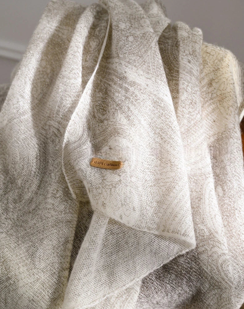 Close-up of an ivory cashmere scarf showing its subtle pattern, soft folds and textured surface.