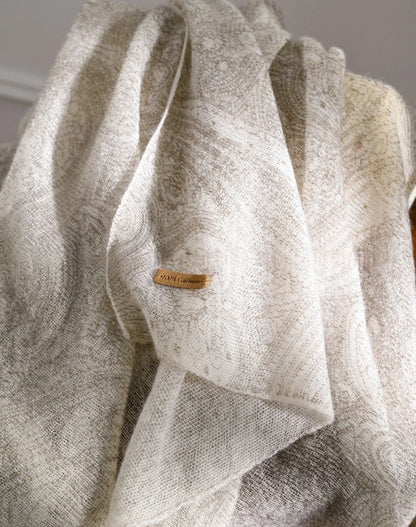 Close-up of an ivory cashmere scarf showing its subtle pattern, soft folds and textured surface.