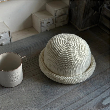 Three-quarter top view of an ivory wool blend knit beanie with a compact rolled edge
