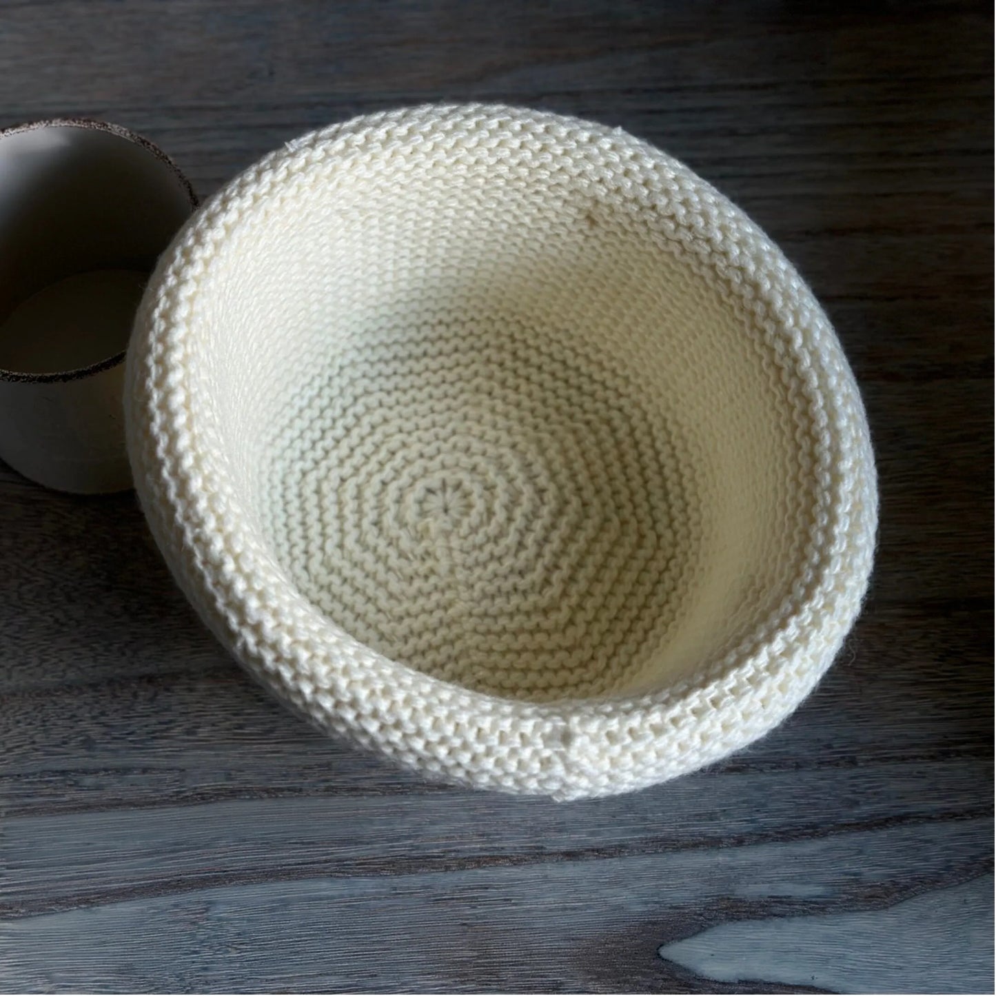 Interior view of an ivory wool blend knit beanie showing spiral construction and a rolled brim