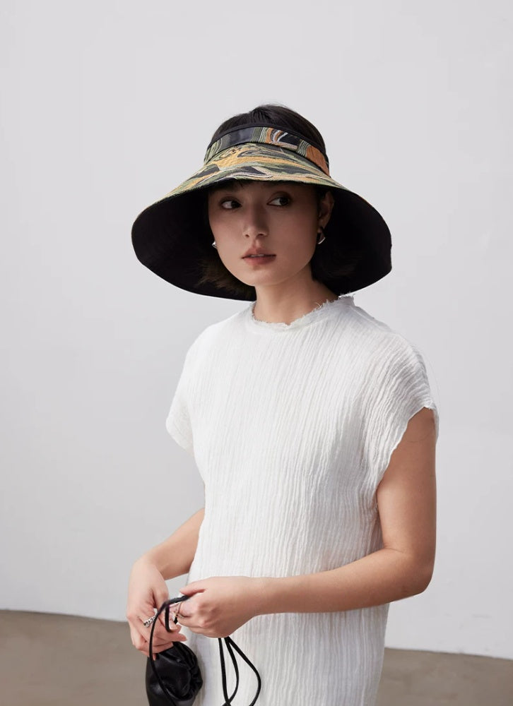 Model wearing a vintage jacquard wide brim sun visor hat with open top design for resort and beach styling.