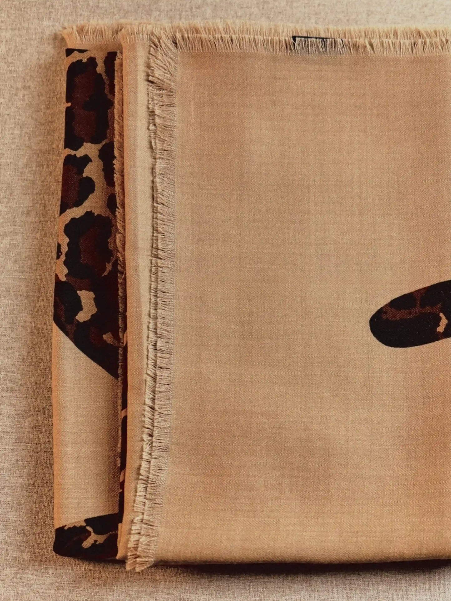 Khaki oversized wool scarf folded to show its lightweight weave and partial leopard graphic
