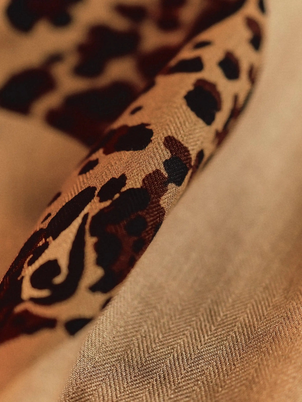 Close-up of the soft wool texture and brown leopard print on a khaki oversized scarf
