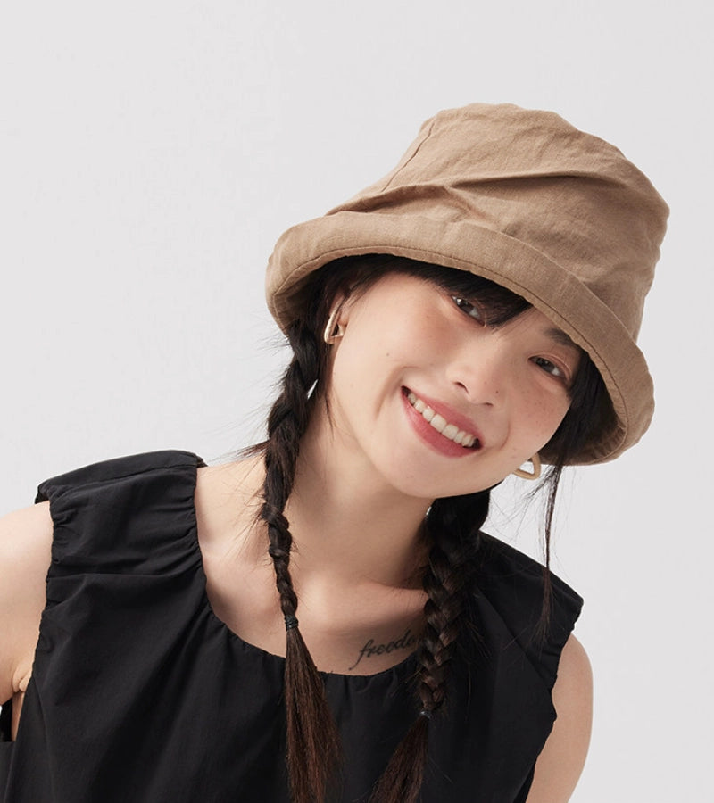 Woman wearing khaki crinkled linen bucket hat with relaxed rolled brim and soft summer style