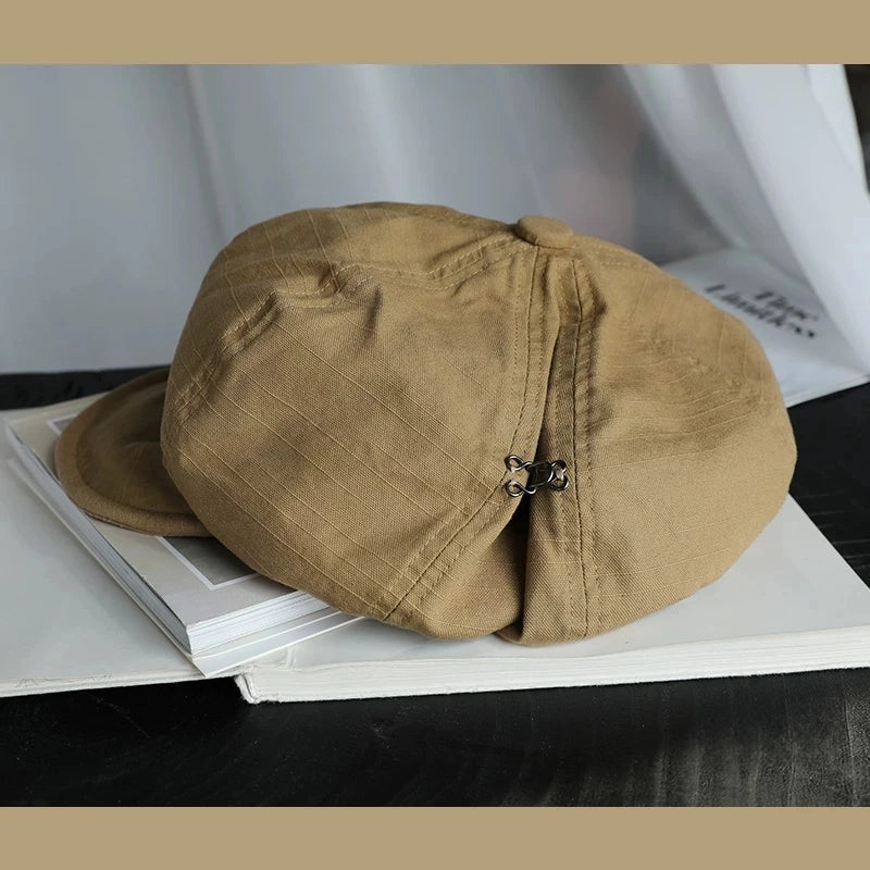 Khaki slouchy cotton beret hat with elastic adjustable fit, displayed on a book for casual everyday styling
