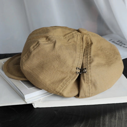 Khaki cotton beret hat displayed on a book, featuring breathable cotton fabric and adjustable elastic detail