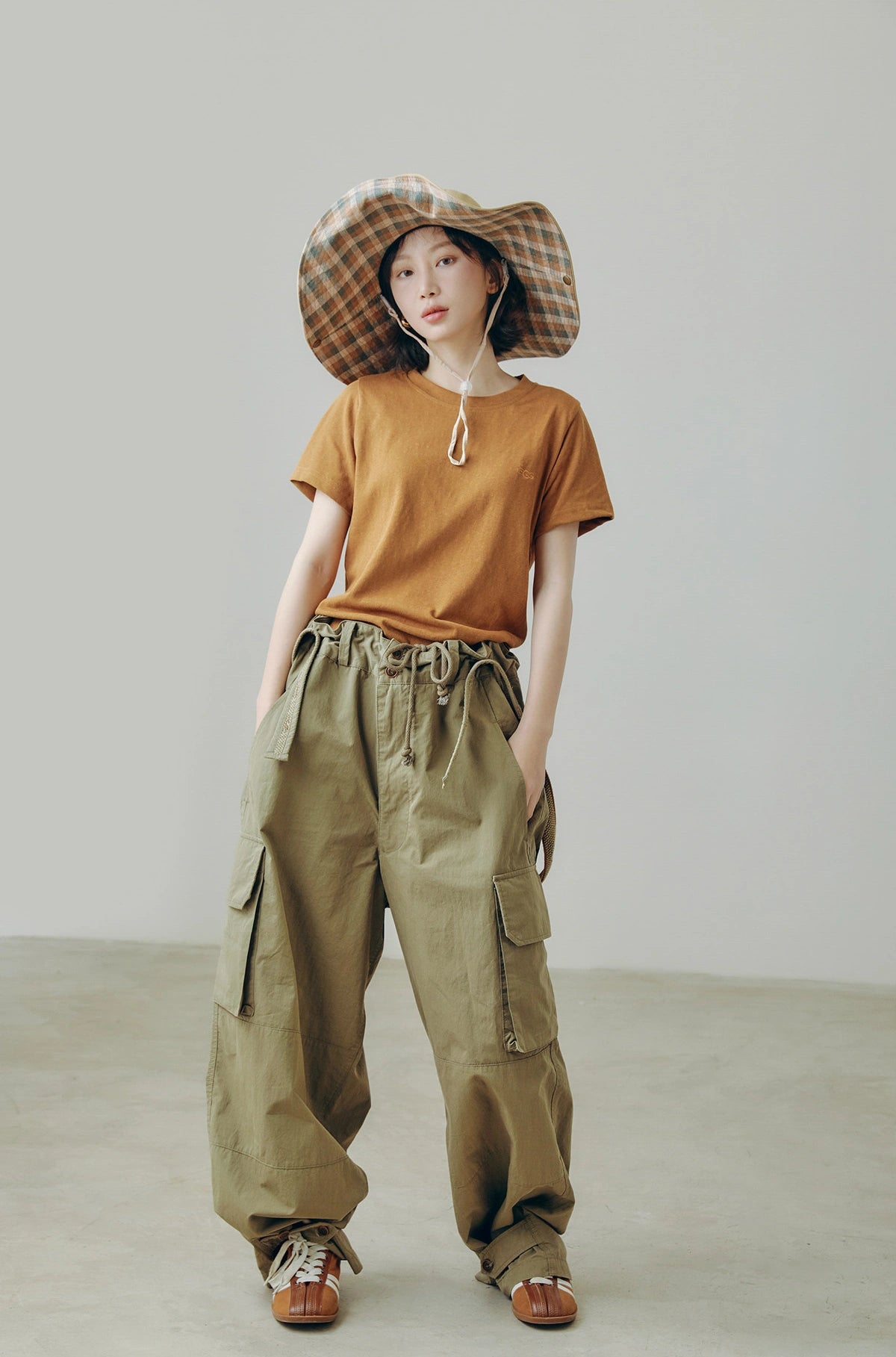 Model wearing khaki wide brim outdoor sun hat with string, styled with cargo pants for city outdoor outfits.