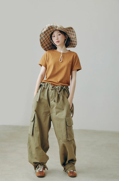 Model wearing khaki wide brim outdoor sun hat with string, styled with cargo pants for city outdoor outfits.