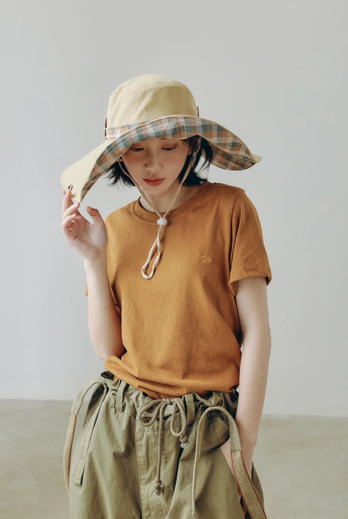 Khaki and plaid wide brim sun hat with adjustable chin string, styled for outdoor travel and daily shade.