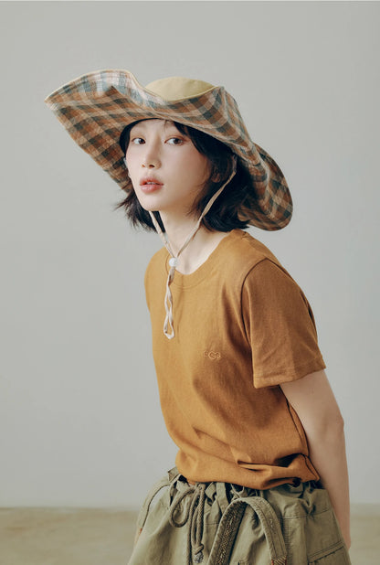 Plaid boonie style wide brim sun hat with string, worn for casual camping, travel, and weekend outfits.