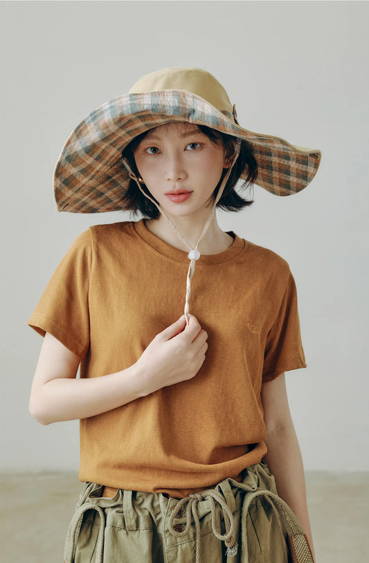 Model wearing plaid wide brim outdoor sun hat with string, styled for relaxed city walks and summer outings.