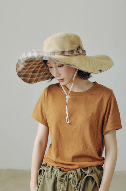 Khaki wide brim sun hat with plaid underside and adjustable string, styled for outdoor summer wear.