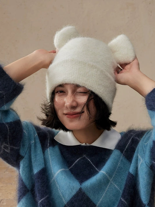 Woman adjusting both rounded ears of a cream white koala ear knit beanie.