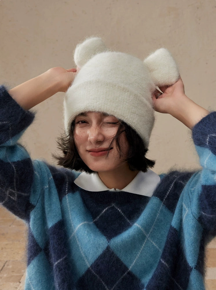 Woman adjusting both rounded ears of a cream white koala ear knit beanie.