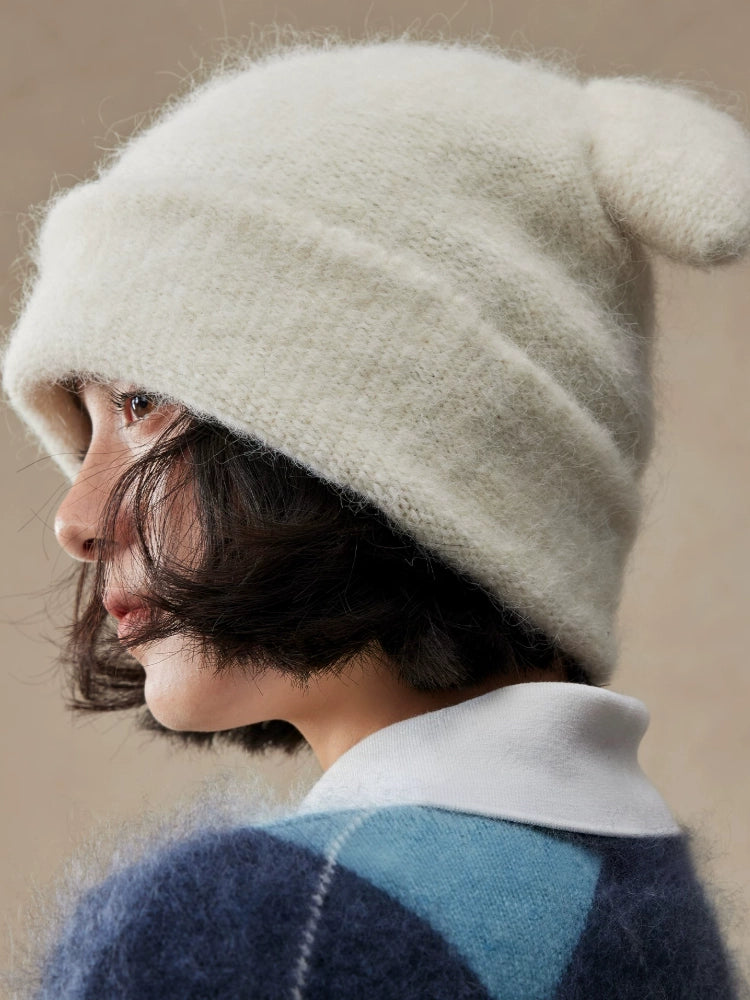 Side view of a cream white koala ear knit beanie with a softly slouched crown.