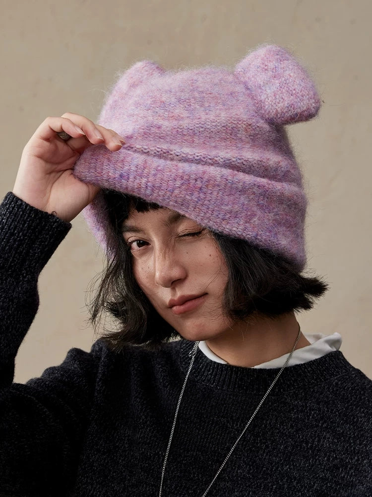 Woman adjusting the folded brim of a misty lavender koala ear knit beanie.