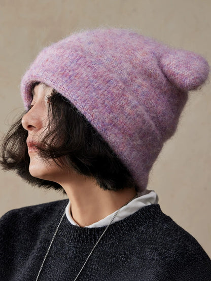 Woman in profile wearing a misty lavender koala ear knit beanie with a black sweater.
