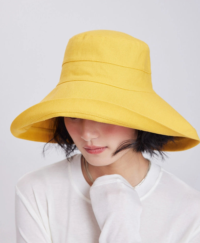 Woman wearing a lemon yellow packable sun hat with a deep wrap-around brim