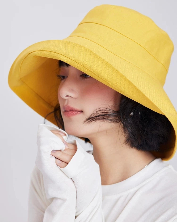 Side view of a lemon yellow wide brim bucket sun hat styled for summer travel and beach wear