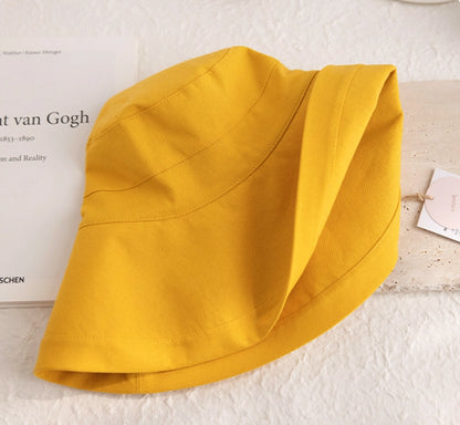 Close-up of a foldable lemon yellow linen cotton sun hat showing its soft brim and fabric texture
