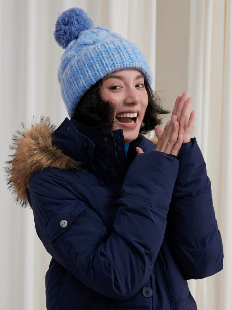 Three-quarter view of a model wearing a light blue pom pom beanie with a folded ribbed cuff.