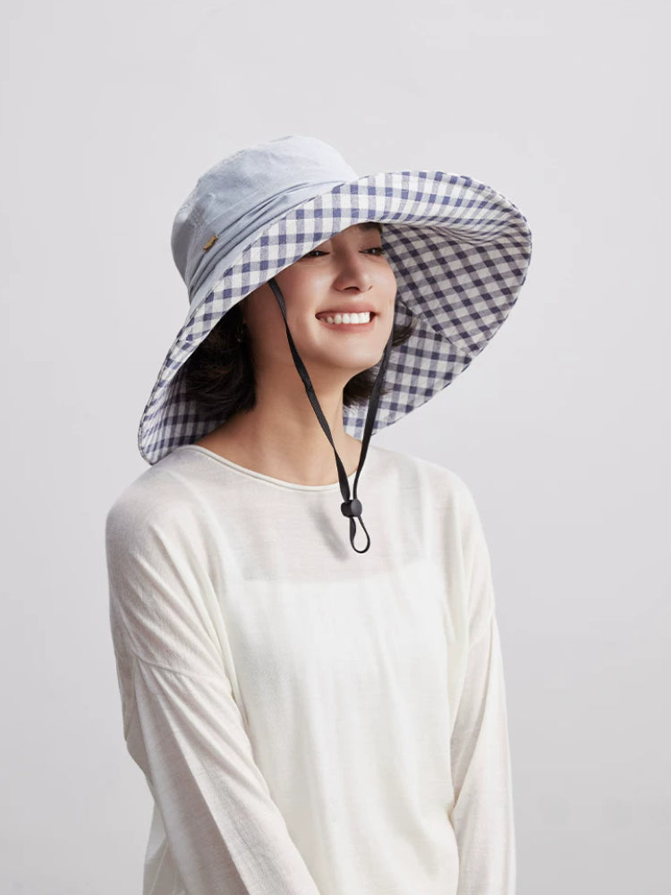Woman styling light blue foldable sun hat with wide brim, plaid lining, and wind cord